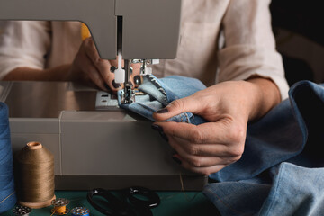 Seamstress using sewing machine for hemming jeans