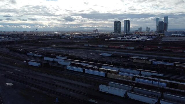 Aerial view flying above heavy shipping containers on Macmillan railroad tracks, Vaughan, Canada skyline at dawn