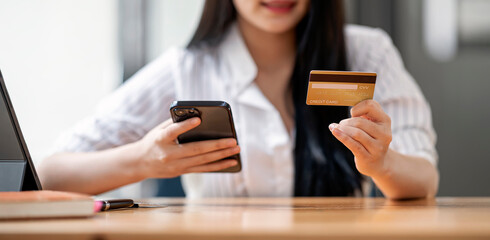 Closeup asian woman holding gold credit card and smartphone, sitting at home, happy satisfied young...