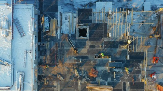 Aerial top-down view of builders lay formwork for pouring concrete for a new floor of a building under construction