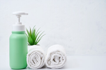 Cosmetic bottles and white towel on table empty space background.Shower items set.Spa objects.Face and body care products.Bathroom tubes.