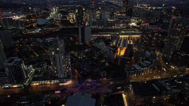 Futuristic Stratford illuminated night time luxury downtown high rise buildings aerial view dolly left