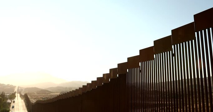 Tecate, Baja California, Mexico - September 14, 2021: Late afternoon sun shines on the USA Mexico border wall as it winds through Tecate.