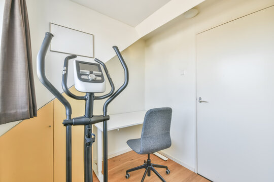 Small and cozy room with an exercise machine and a work area