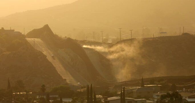 Tecate, Baja California, Mexico - September 14, 2021: Late afternoon sun shines on the USA Mexico border wall as it winds through Tecate.
