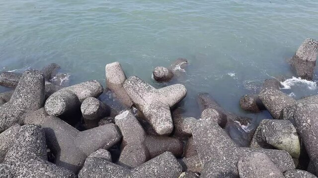 Tetrapod is a concrete structure that has four sides like a cylinder, serving as a protective unit on the breakwater.Marine Drive Concrete Blocks at Sea Shore
