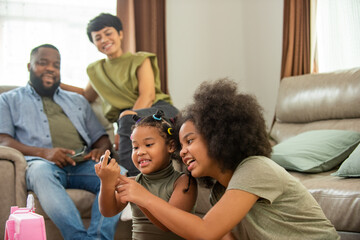 African family spending time together at home. Cute child girl kid sibling playing toy together on the floor in living room. Little daughter enjoy and having fun leisure activity with parents at home.