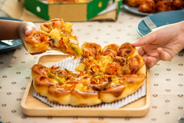 African family parents and two little daughter eating fried chicken and pizza on table for dinner together. Father and mother and cute child girl kid enjoy eating and sharing a meal together at home