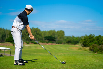 Confidence Asian man golfer holding golf club hitting golf ball on the green at golf course in...