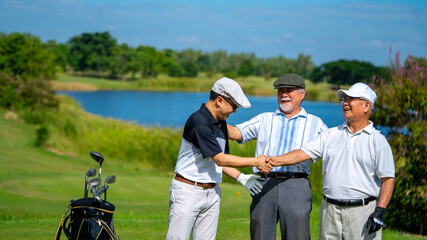 Group of Asian people businessman and senior CEO enjoy outdoor sport lifestyle golfing together at golf country club. Healthy men golfer shaking hand after finish game on golf course at summer sunset