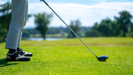 Confidence Asian man golfer holding golf club hitting golf ball on the green at golf course in sunny day. Healthy male enjoy outdoor lifestyle activity sport golfing at country club on summer vacation