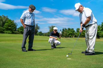 Group of Asian people businessman and senior CEO golfing near the hole on golf fairway together at...