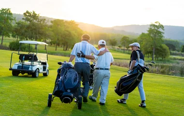 Deurstickers  Group of Asian people businessman and senior CEO enjoy outdoor sport golfing together at country club. Healthy men golfer holding golf bag walking on fairway with talking together at summer sunset © CandyRetriever 