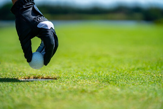 Close Up Hand Of Asian Senior Man Golfer Picking Golf Ball Out Of The Hole On Green At Golf Course. Healthy Male Enjoy Outdoor Lifestyle Activity Sport Golfing At Country Club On Summer Vacation