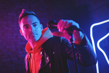 A singer man at the scene with the microphone in the neon lights concept.