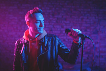 A singer man at the scene with the microphone in the neon lights concept.