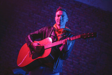 A singer with a guitar at the scene in the neon lights.