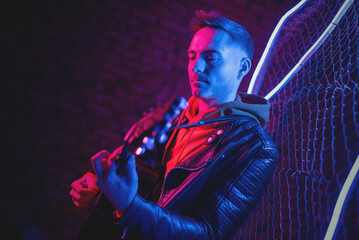 A singer with a guitar at the scene in the neon lights.