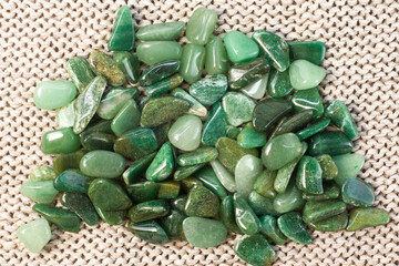 Macroshooting of natural mineral rock specimen - tumbled green aventurine gemstone on beige background