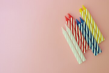 Colourful candles isolated in the green rope on pink background. Birthday,Christmas and special greetings concept. © Hari