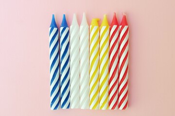 Colourful candles isolated in the green rope on pink background. Birthday,Christmas and special greetings concept. © Hari