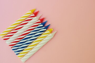 Colourful candles isolated in the green rope on pink background. Birthday,Christmas and special greetings concept. © Hari