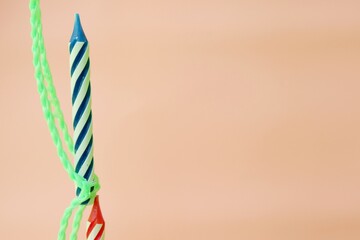 Colourful candles isolated in the green rope on pink background. Birthday,Christmas and special greetings concept.