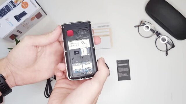 Unboxing and showing features of an oldschool dual sim flipphone for grandma, then inserting battery.