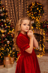 girl in a red dress at home by the Christmas tree and fireplace