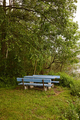 Blaue verwitterte Picknicksitzgruppe in grünem Wäldchen
