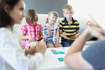Fototapeta premium Cheerful children playing card game with parents at home