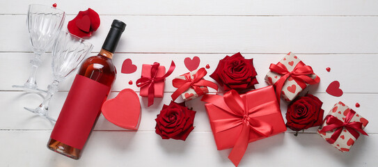 Composition with bottle of wine, gifts and roses on white wooden background