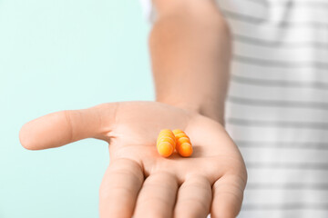 Young man with yellow earplugs on blue background, closeup