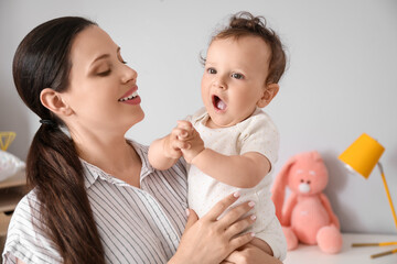 Young mother holding her little baby in bedroom