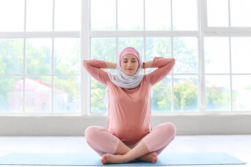 Young pregnant Muslim woman exercising on mat in gym