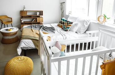 Interior of light modern bedroom with crib and big window