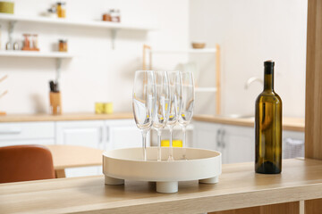 Fototapeta na wymiar Bottle of wine and tray with glasses on shelf in modern kitchen