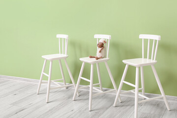 White modern chairs with sheep toy near color wall in child room