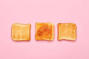 Tasty pear jam and bread on pink background