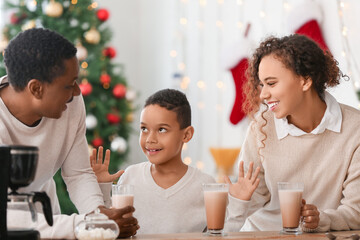Happy African-American family drinking tasty hot chocolate at home on Christmas eve
