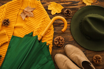 Composition with umbrella, shoes, hat and autumn decor on wooden background, closeup