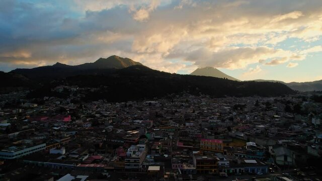 Drone Aerial View Of Urban Colonial Cityscape Near Two Volcanos During Golden Hour Sunset Dusk In Quetzaltenango Xela Guatemala. Volcan De Cerro Quemado And Volcan Santa Maria.