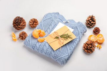 Beautiful winter composition with sweater, card, tangerines and cones on white background