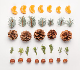 Beautiful winter composition with coniferous branches, cones, hazelnuts and tangerine segments on white background