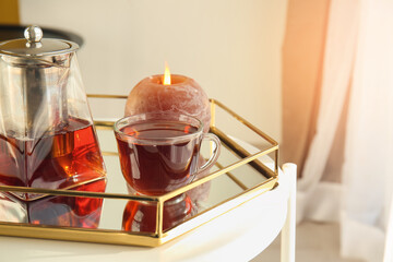 Glass cup of tasty tea and pot on table at home