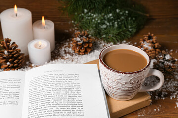 Cup of tasty coffee, book and Christmas decor on wooden background