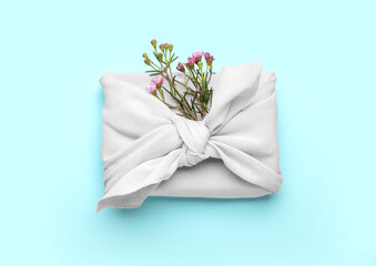 Gift box wrapped in cotton fabric with flowers on blue background