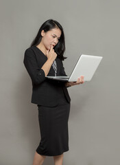 Young woman holding laptop with bad feeling facial expression while biting finger