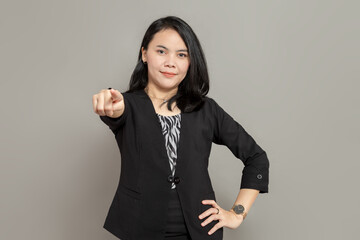 Young business woman in black suit is pointing ahead with smile facial expression