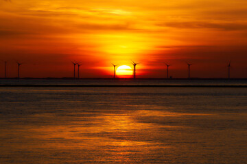 Offshore wind park on the sea. Wind turbines in late evening at sunset. Netherlands, near Zeeland Bridge.